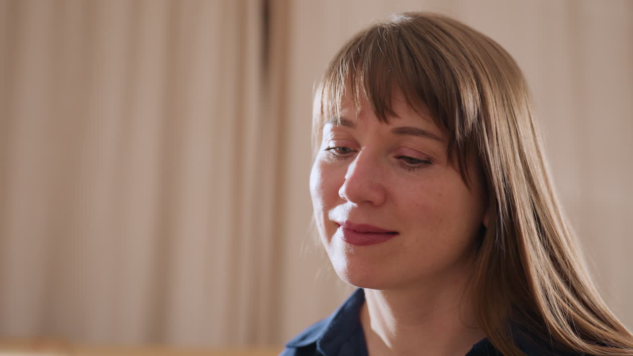 Medium view of professional woman smiling softly in bright calm room, expressing warmth and attentive presence during peaceful moment of connection and reflection in therapeutic setting