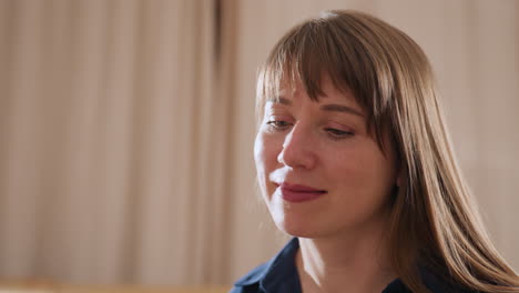 medium view of professional woman smiling softly in bright calm room, expressing warmth and attentive presence during peaceful moment of connection and reflection in therapeutic setting