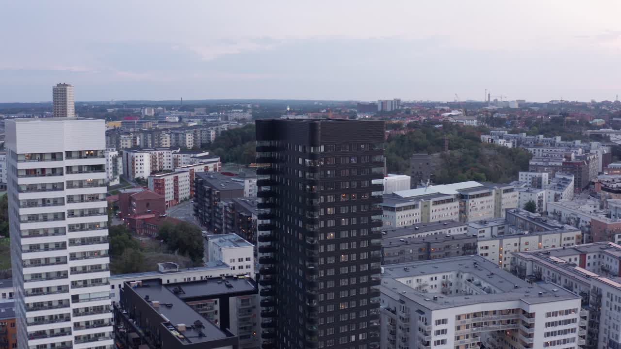 Drone footage of a black and a white high-rise residential building with modern design and architecture in &Aring;rstadal, Stockholm