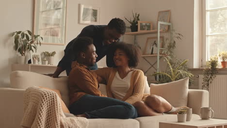 three people smiling and interacting in a cozy living room
