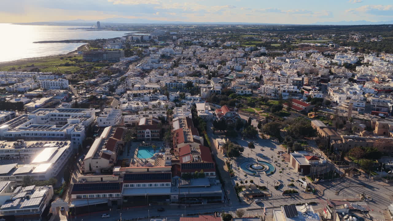 Vista aérea de drone de Aiya Napa, Chipre, com litoral, paisagem urbana e o Mar Mediterrâneo sob a luz quente do sol.