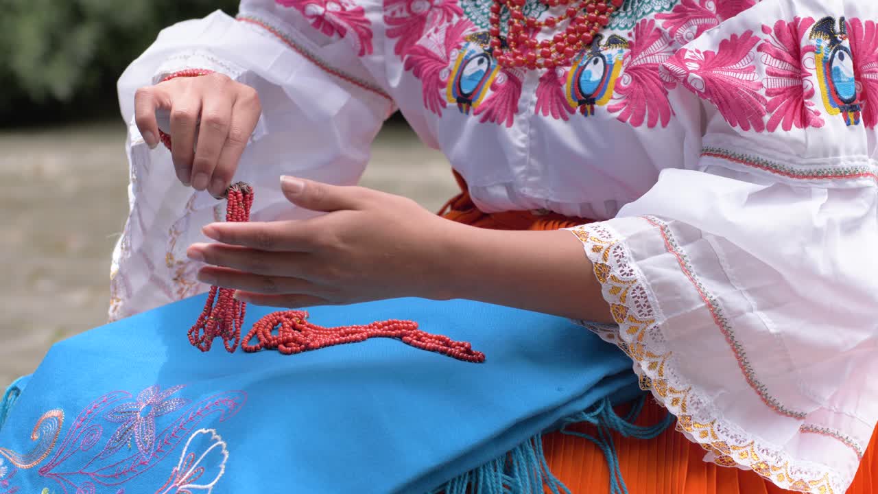 clip cinematográfico en cámara lenta de una joven descansando sus collares rojos en el traje tradicional de cayambeñas en ecuador