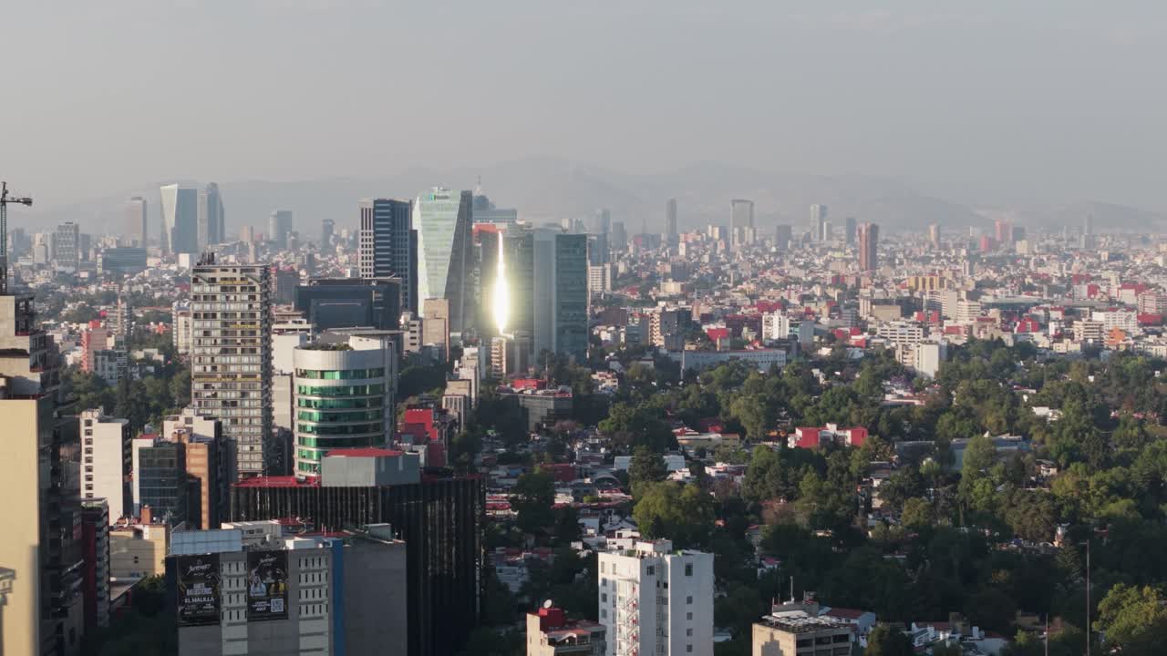 Drone aerial view of a sunny, smoggy afternoon in southern CDMX, sun reflecting on a building