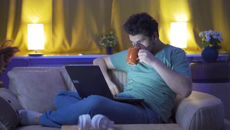 hombre viendo una película en la computadora portátil por la noche en casa.
