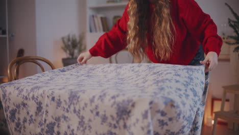 blond woman putting tablecloth on table