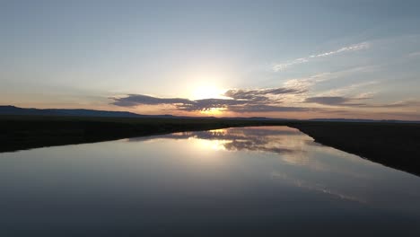 aerial drone shot following a river during sunrise in mongolian steppes