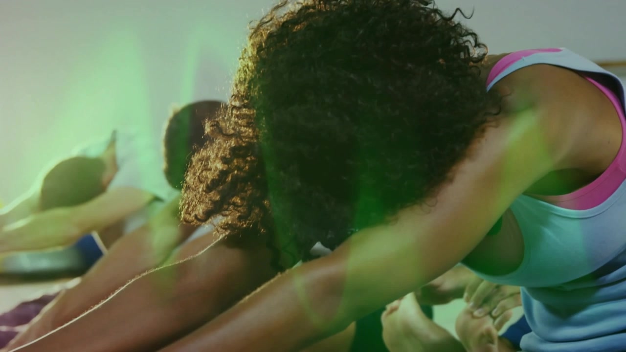 Video verticale: Istruttrice che guida una donna e la classe che si piegano in avanti per il fitness, con una sfumatura verde che attraversa i busti.