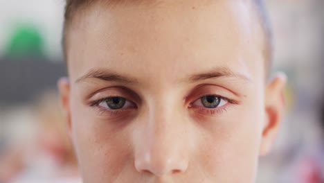 retrato de un escolar caucásico feliz en un escritorio en el aula de la escuela