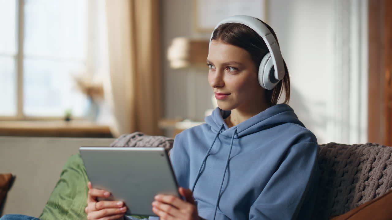 Woman using tablet with headphones at home