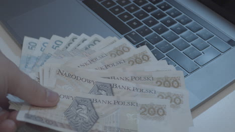 person lying zloty banknotes hand fan on digital laptop,close up shot