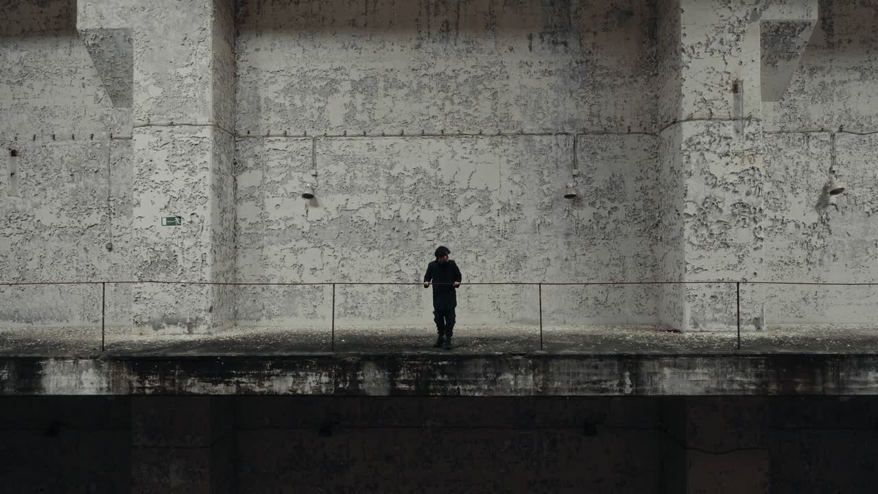 Solitary Man Walking Along a Gritty Concrete Wall