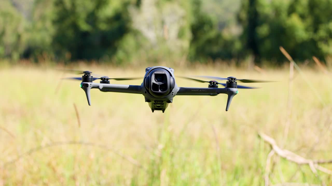Drone flies and hovers over grassy field