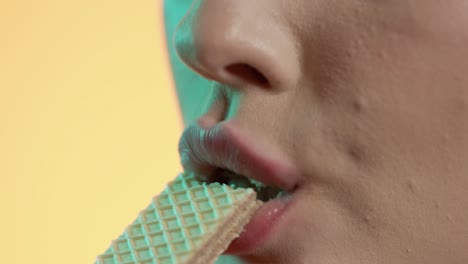 mujer comiendo y mordiendo un bocadillo de waffle, masticando boca primer plano en fondo naranja