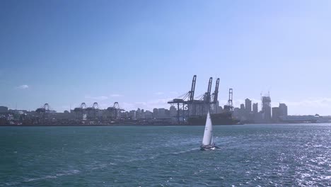 slowmo - small sailboat passing with auckland harbour in background, new zealand