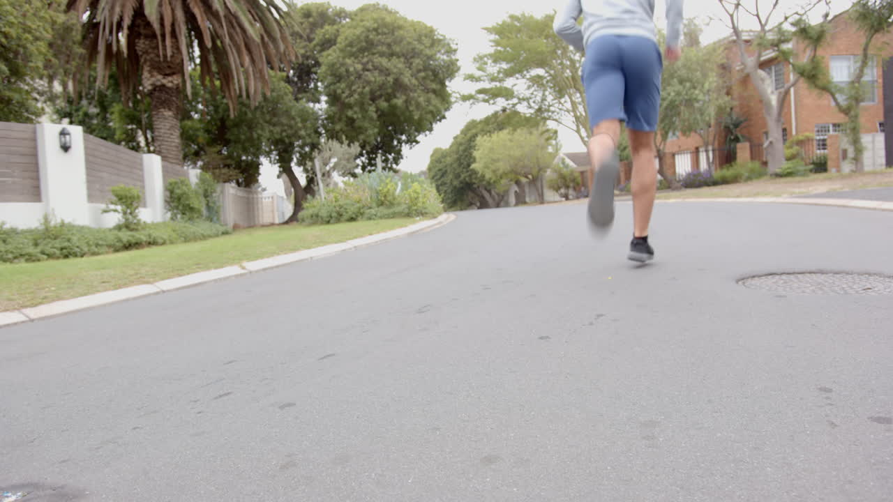 Jogging on suburban street, man in athletic wear exercising outdoors, copy space