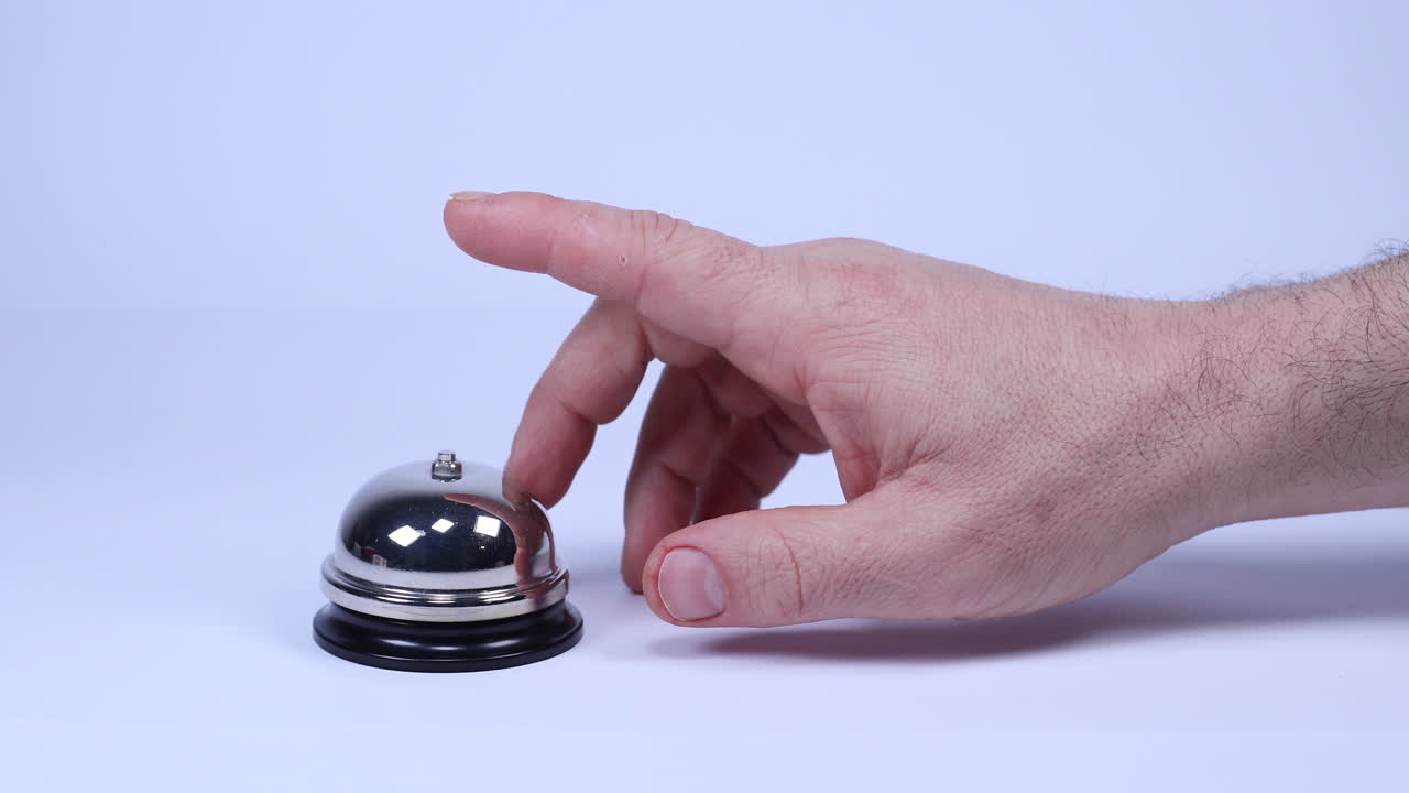 Hand moves into frame and the index finger taps concierge bell twice impatiently