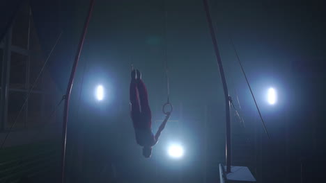 a still shot of a guy working out on the still rings a gymnastics apparatus that is extremely hard in slow motion 180 fps.