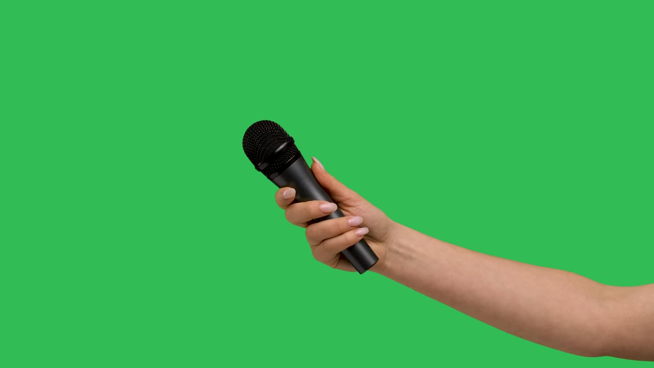 Female hand holding microphone against background green screen chroma key. Close up mic, interview, live press conference, karaoke, singer performance. Slow motion