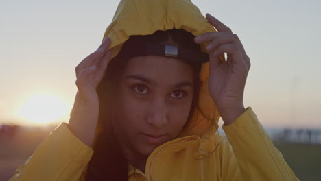 close-up-portrait-of-mixed-race-teenage-girl-removing-hood-looking-confident-wearing-cute-hat-enjoying-park-at-sunset