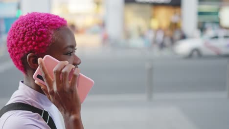 young woman with pink hair using a smartphone on the street