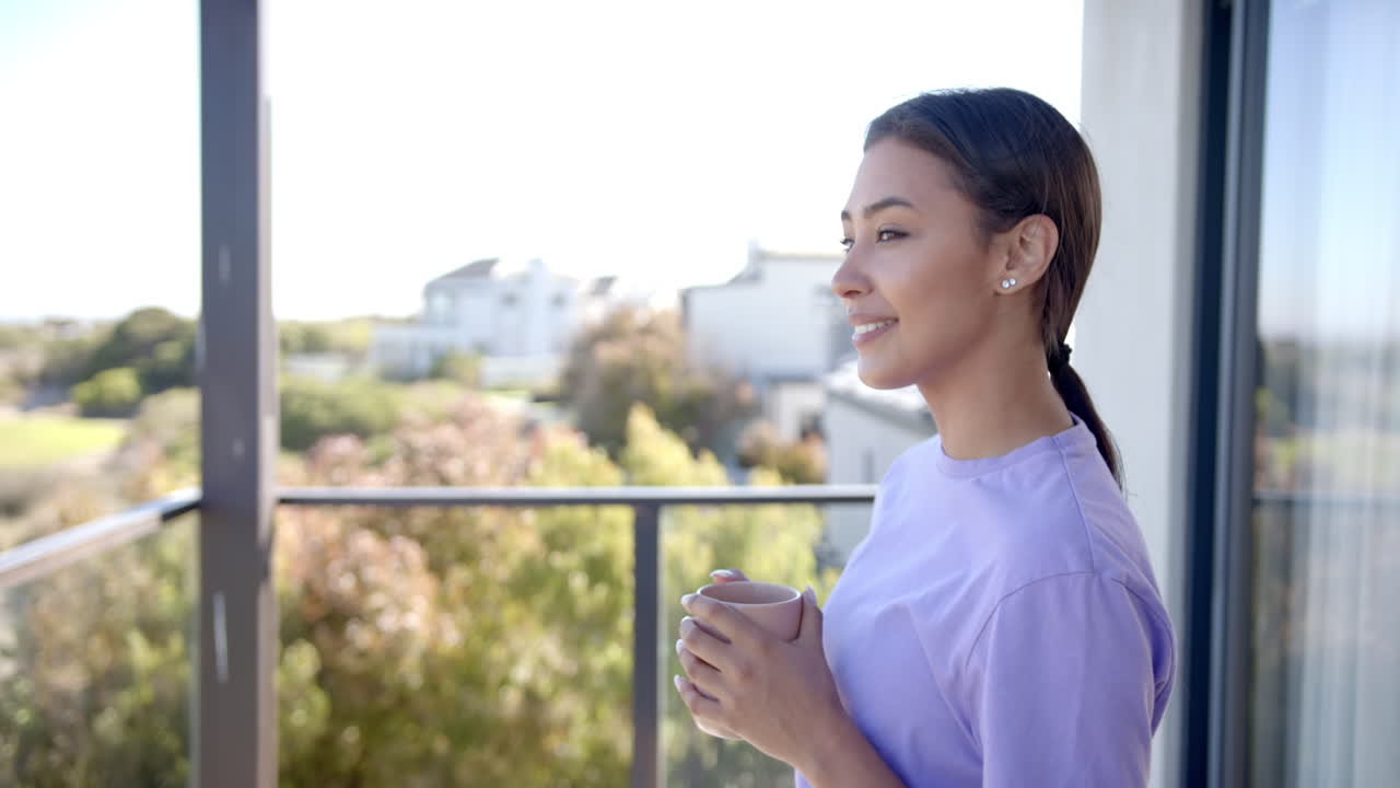 Smiling woman holding coffee cup, enjoying morning on balcony at home, copy space