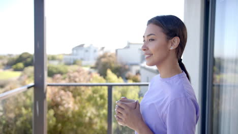 smiling woman holding coffee cup, enjoying morning on balcony at home, copy space