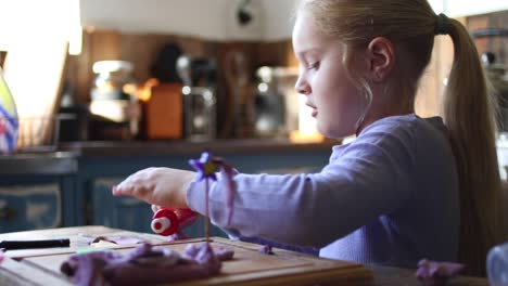 close up footage of a young five year old girl playing with clay in the kitchen of the house she lives in