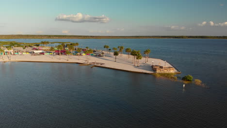 Aerial-low-arc,-small-little-island-with-desert-beach-at-sunset