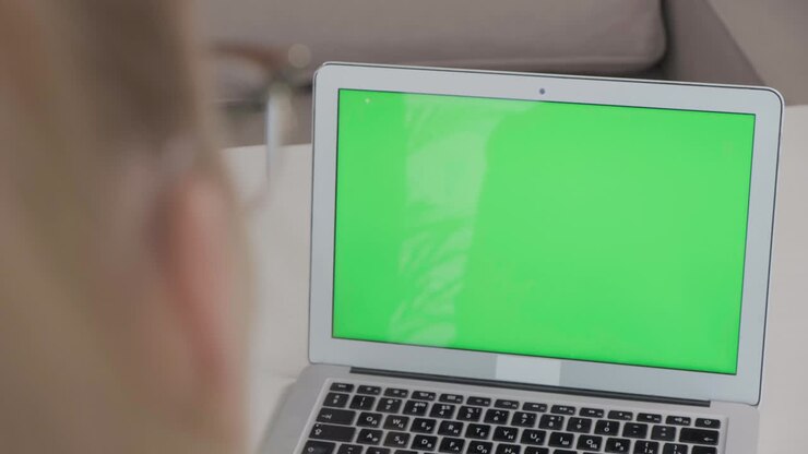 Close up laptop on table with blank green screen, white table.