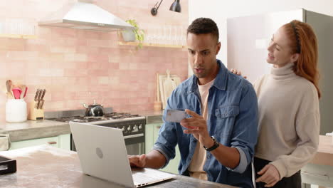 happy couple shopping online with credit card and laptop in cozy kitchen