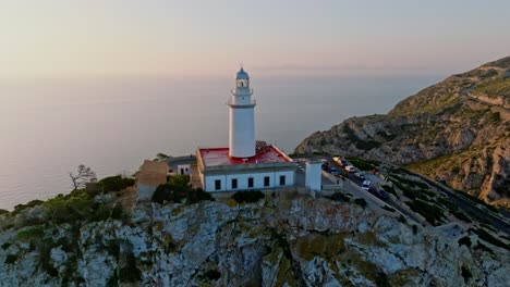 Atemberaubende-Luftaufnahme-Des-Leuchtturms-Von-Formentor-Mit-Der-Sonne,-Die-Sich-Im-Meer-Spiegelt