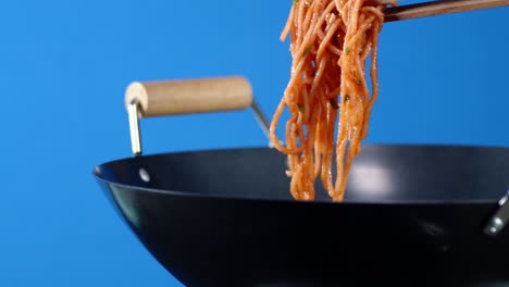 male hand take wooden tongs boiled pasta spaghetti from pan.