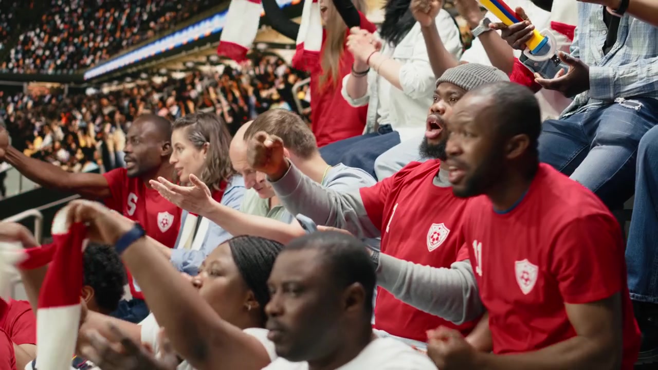 Aficionados afroamericanos siguiendo el marcador en vivo para un boleto de apuesta en una aplicación móvil
