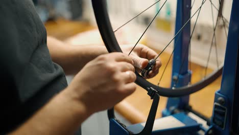 a bicycle mechanic fixes and adjusts the spoke tension on bike bike wheel in a repair shot