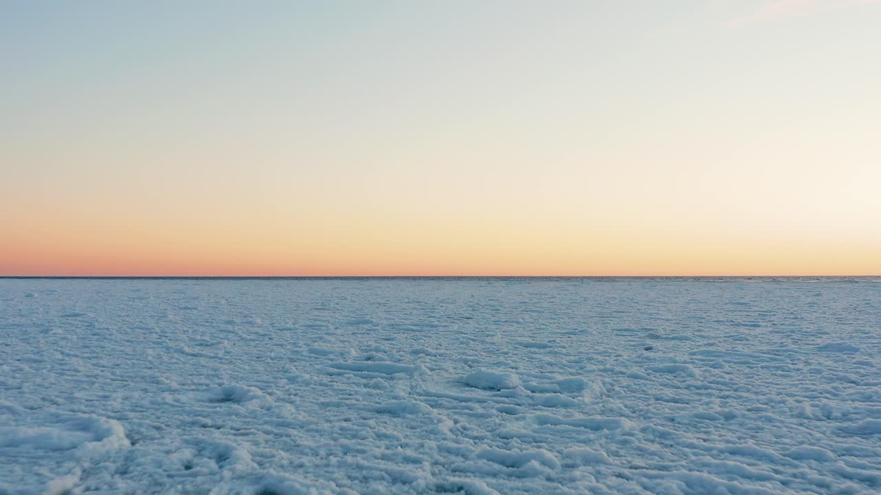 해가 질 때 라트비아 발트해에 부서진 얼음 조각으로 이루어진 크고 하얀 들판 위를 낮고 빠르게 날아다닌다