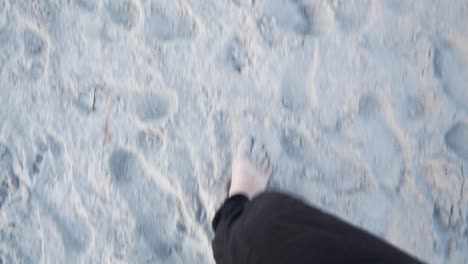 POV-of-female-legs-walking-barefoot-on-sand-at-dusk