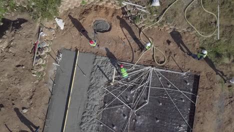 rising aerial reveals construction crew pouring concrete pad for home