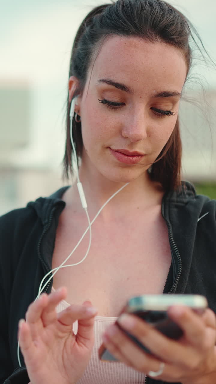 Woman using smartphone with earphones outdoors