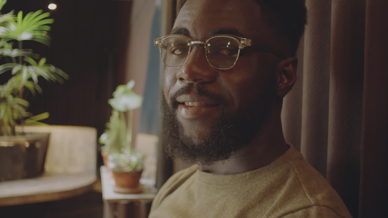 A man with glasses and a beard poses indoors