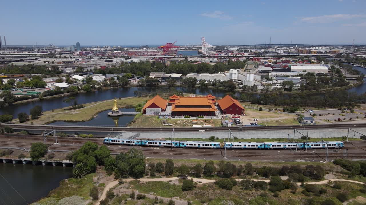 Aerial drone follows Metro train heading towards Melbourne city over nature reserve