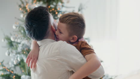 un niño pequeño saluda y abraza a su padre contra el árbol