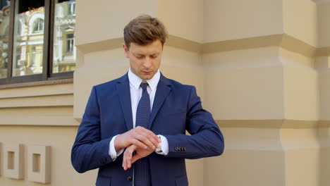 Primer-Hombre-De-Negocios-Esperando-Al-Aire-Libre.-Chico-Comprobando-La-Hora-En-Un-Reloj-Inteligente-En-La-Calle