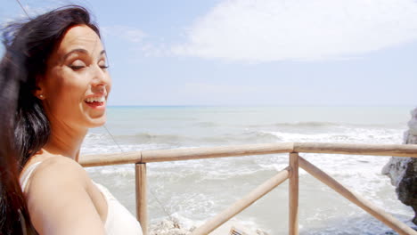 brunette woman taking self portrait by ocean