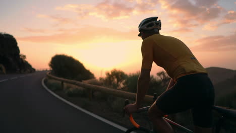 the athlete on a bike is seen in slow motion conquering a mountain serpentine, cherishing the island's view, epitomizing a devotion to a healthy lifestyle at sunset