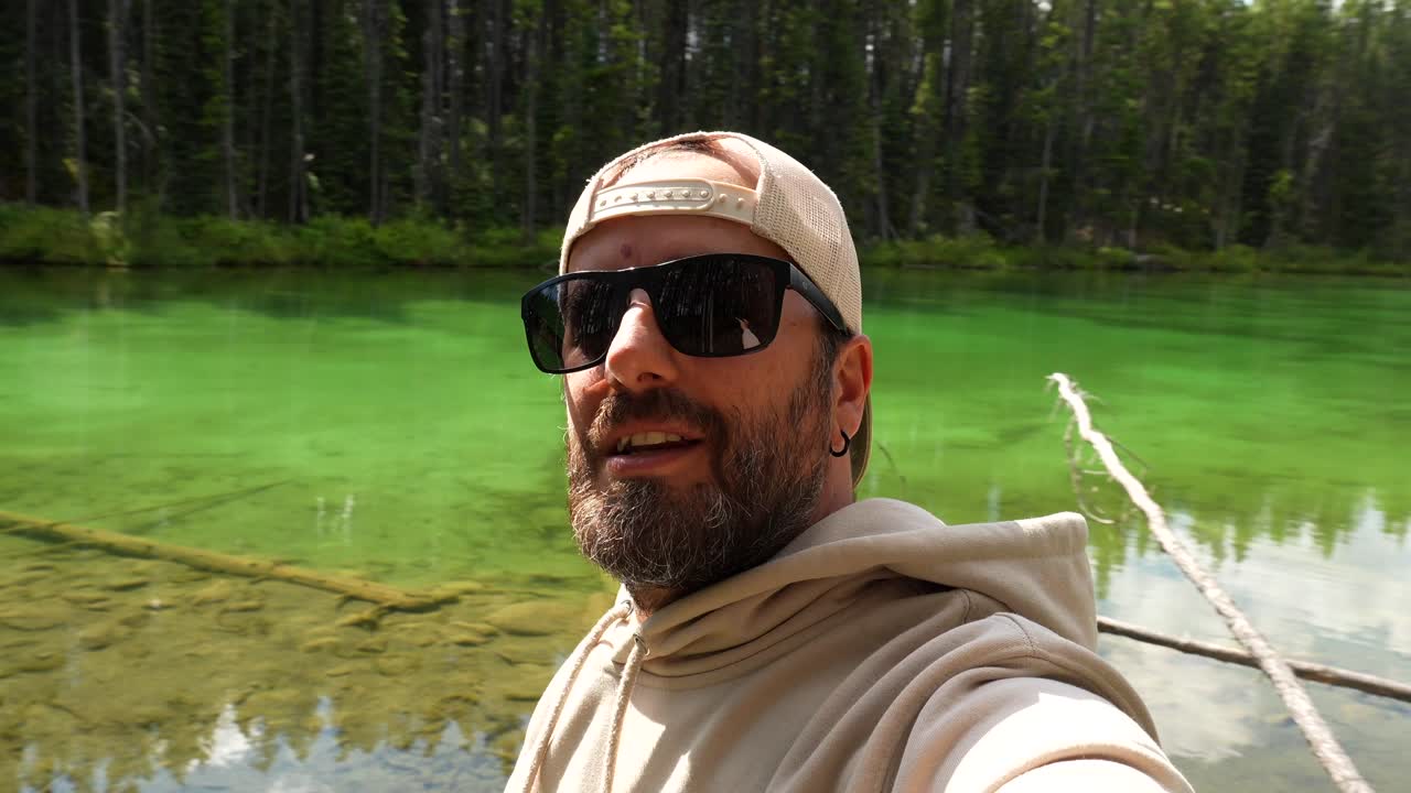 Uomo con occhiali da sole vicino a un lago verde