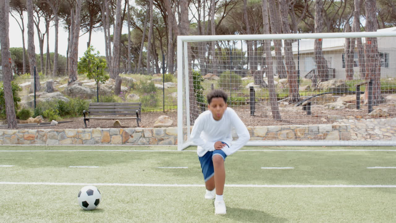 Young boy kneeling on soccer field, preparing for game near goalpost, copy space