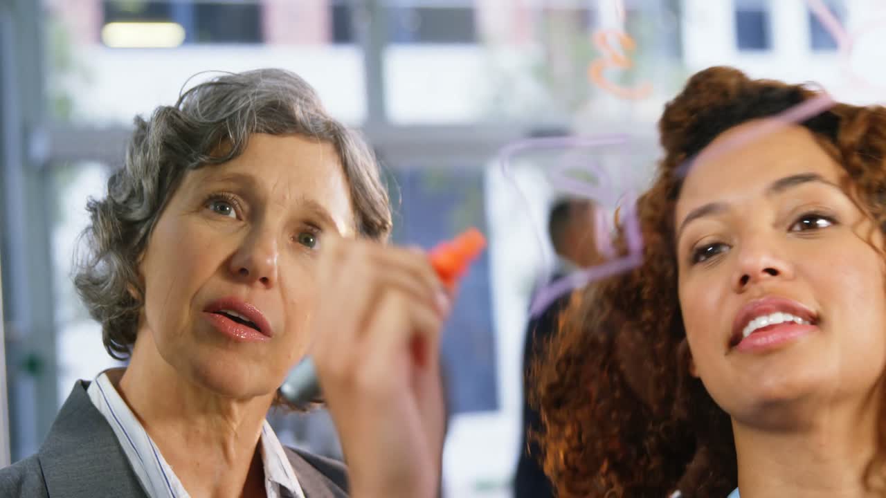 colegas de negocios hablando mientras escriben en una ventana de vidrio