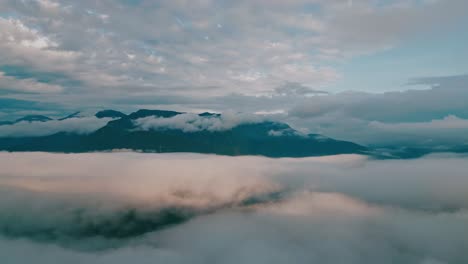 Drift-through-the-clouds-in-this-entrancing-drone-footage,-as-elegant-birds-glide-past-and-grand-mountain-peaks-ascend-in-the-background,-perfectly-accentuating-the-lush-Yungas-cloud-forest-below