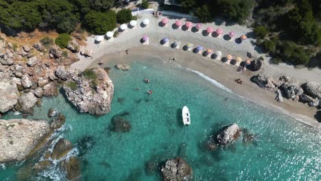 Un-Dron-Desciende-Mientras-El-Agua-Clara-Choca-Contra-Las-Costas-Arenosas-De-La-Riviera-Albanesa.