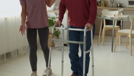 caregiver helping elderly man to use walker